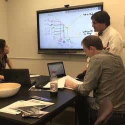 Three graduate students examining a graph