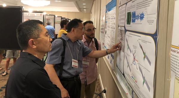 A student and two faculty review a science poster presentation