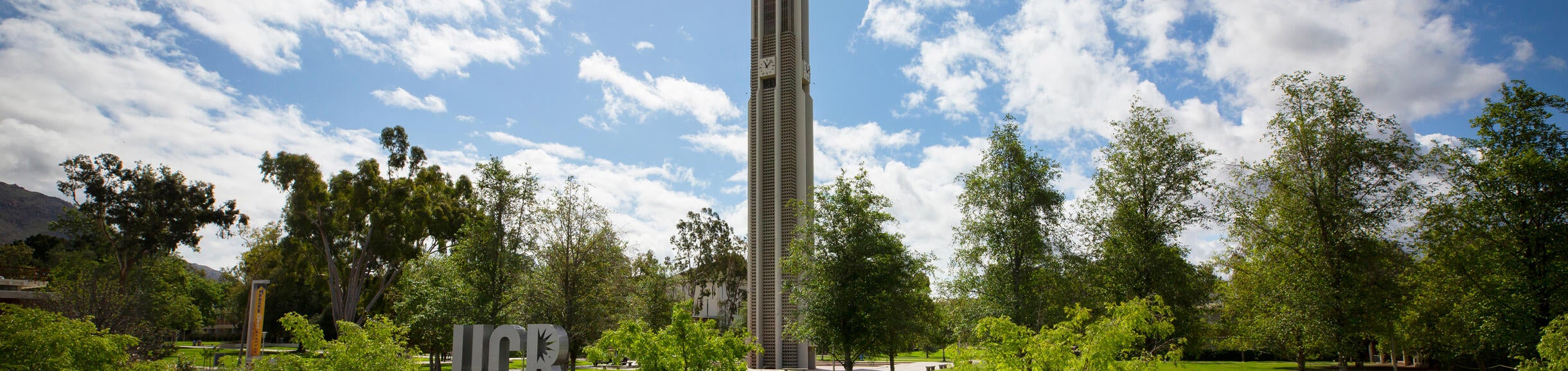 UCR Bell Tower with clouded sky and green foliage 
