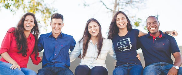 students sitting in a row outdoors smiling at camera