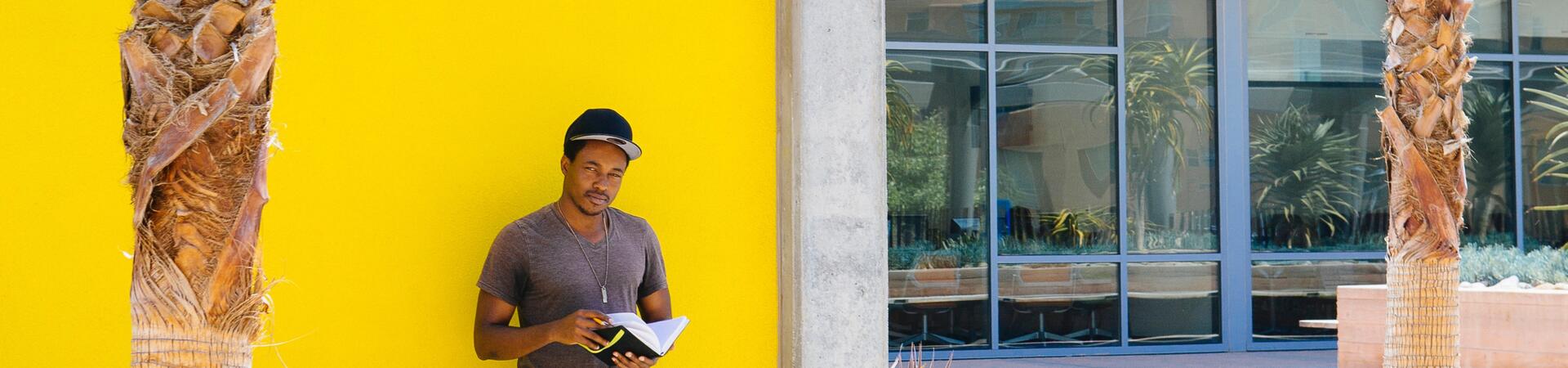 Student standing by yellow wall