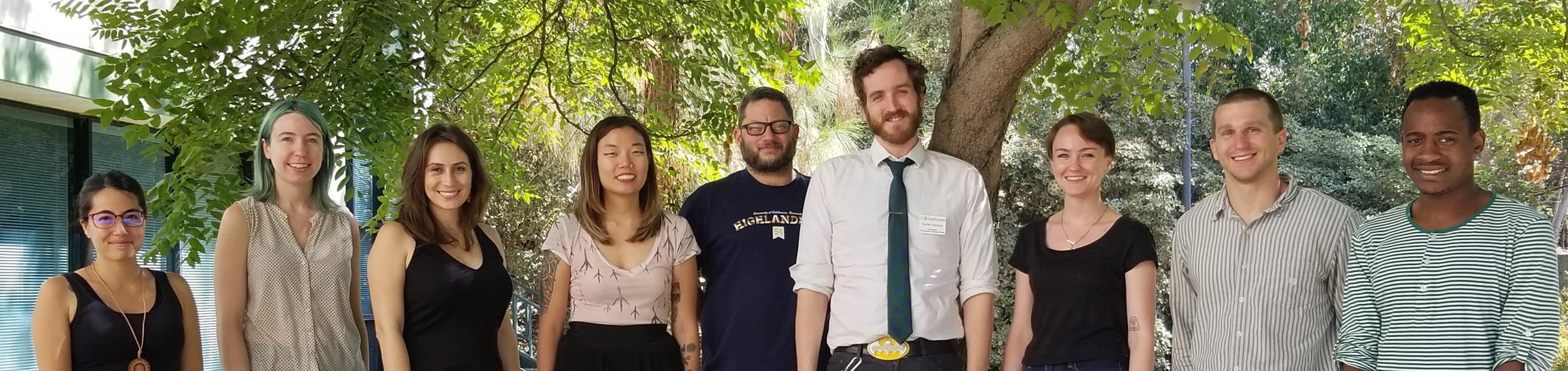 Photo of Nine Graduate Students Standing Under a Tree